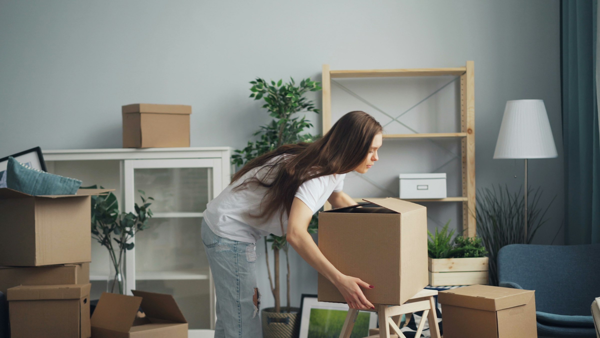 Person carrying moving boxes in a bright living room